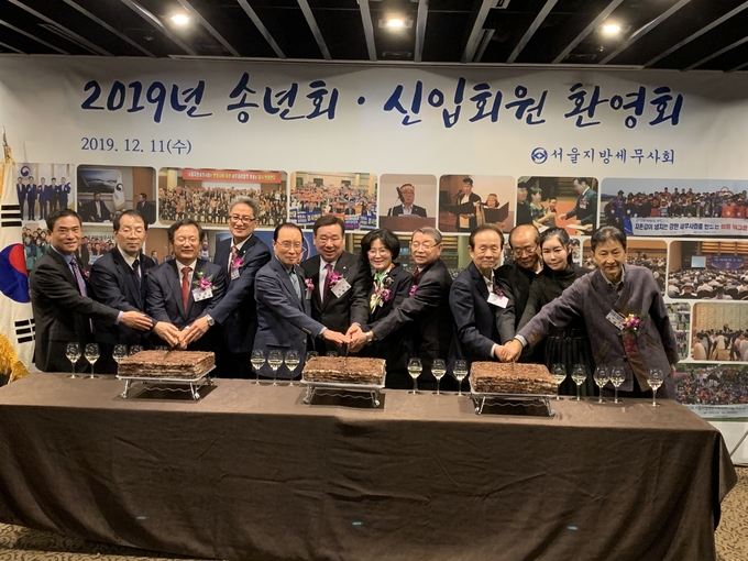 참석 내빈들이 송년 모임을 축하하며 기념 떡을 자르고 있다.