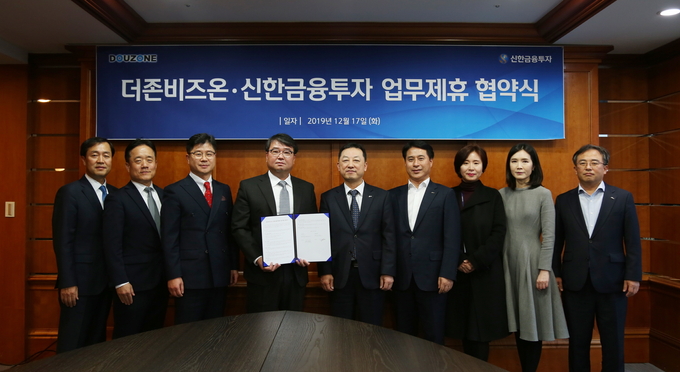 더존비즈온 김용우 대표(사진 왼쪽 네 번째)와 신한금융투자 김병철 대표(사진 왼쪽 다섯 번째)가 업무협약서를 교환하고 있다.