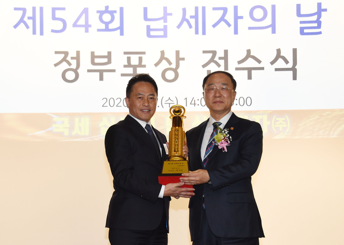 홍남기 경제부총리 겸 기획재정부 장관(오른쪽)이 4일 서울 중구 은행연합회에서 열린 '제54회 납세자의 날' 정부포상 전수식에서 삼성전자 관계자에게 국세 10조원 탑을 전수하고 있다.(사진:기재부 제공)