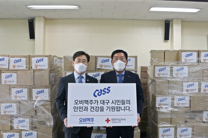오비맥주 경북권역 박인수 전무(오른쪽)와 대한적십자사 대구지사 송준기 지사장이 지난 3월3일 대한적십자사 대구지사 별관에서 열린 구호물품 전달식에서 기념촬영을 하고 있다.