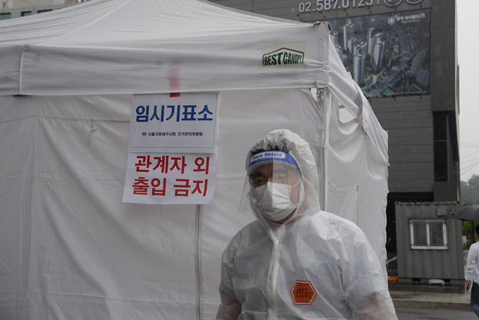 발열 등 이상증세를 보이는 의심자를 위한 임시기표소가 야외에 설치됐다. 방호복을 입은 관계자가 대기하고 있다.