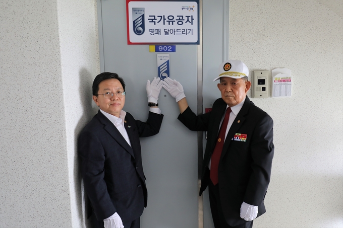 노석환(왼쪽) 관세청장과 김흥겸 국가유공자가 출입문에 명패를 부착하고 기념촬영을 하고 있다.