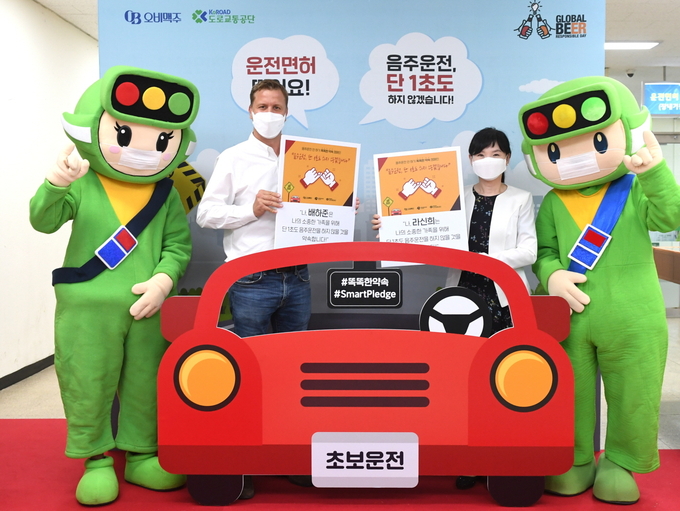 오비맥주 배하준 대표(왼쪽)와 강남운전면허시험장 라신희 단장이 도로교통공단 마스코트 호둥이와 함께 기념촬영을 하고 있다.