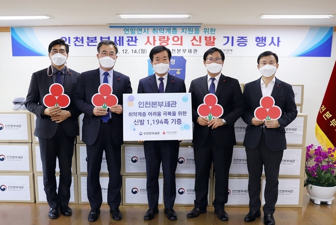 김윤식<중앙> 인천본부세관장이 사회복지공동모금회에 신발을 전달하고 있다.
