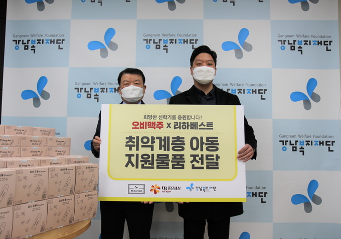 리하베스트 민명준 대표(오른쪽)가 오비맥주와 함께 취약계층 아동을 위해 마련한 문구용품과 고단백 리너지바를 강남복지재단 김용주 상임이사에게 기탁하며 기념촬영을 하고 있다.