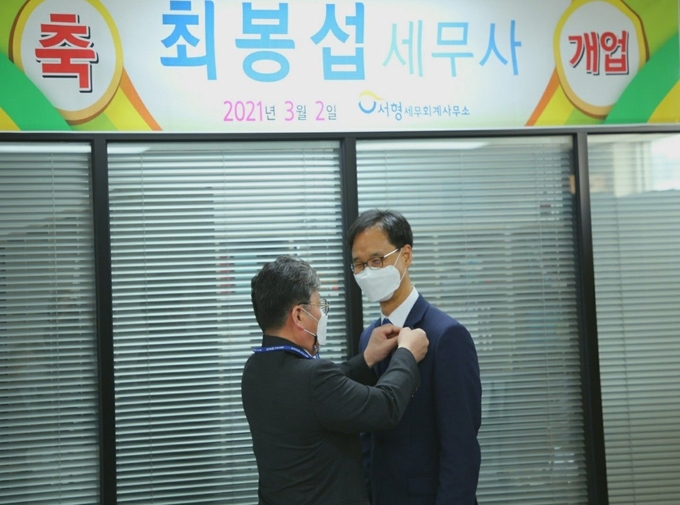 정성균 광주지방세무사회장이 2일 개업한 최봉섭 세무사에게 세무사 배지를 패용하고 있다.