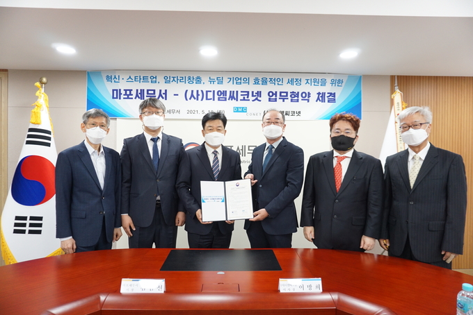 김남선 마포세무서장<왼쪽 세번째>과 이방희 디엠씨코넷 이사장<네번째>이 관계자들과 함께 업무협약을 맺고 있다. 