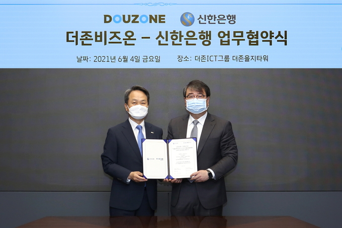 더존비즈온 김용우 대표(오른쪽)와 신한은행 진옥동 은행장이 협약서를 교환하고 있다.