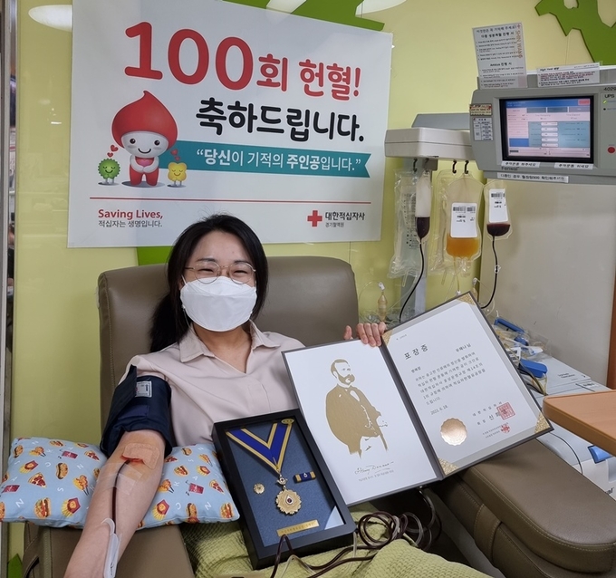우해나 중부지방국세청 조사관이 적십자혈액원 산본센터에서 채혈하는 와중, 대한적십자사로부터 헌혈유공 포장장을 받고 있다.