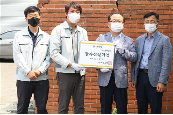 장수성실기업 (주)제일금속의 입간판을 들고 관계자들이 기념촬영하고 있다. 