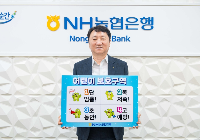 권준학 은행장이 어린이 교통안전 릴레이 챌린지 피켓을 들고 기념촬영하고 있다.