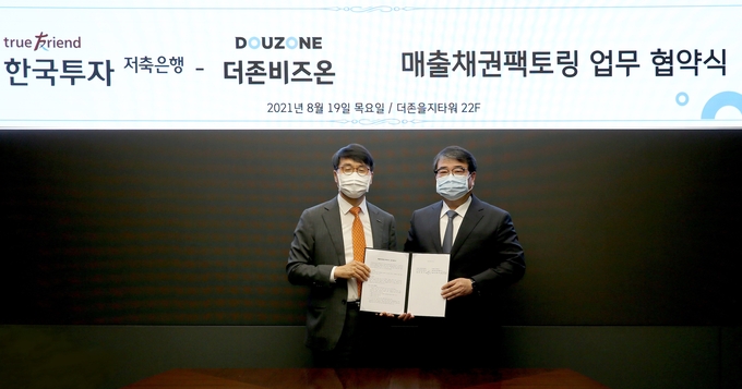 더존비즈온 김용우 대표(오른쪽)와 한국투자저축은행 권종로 대표가 WEHAGO 기반 매출채권팩토링 사업’ 에 관한 업무협약서를 교환하고 있다.