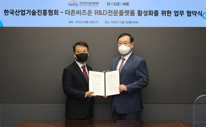 더존비즈온 이강수 사장(오른쪽)과 한국산업기술진흥협회 마창환 상임부회장이 업무협약서를 교환하고 있다.