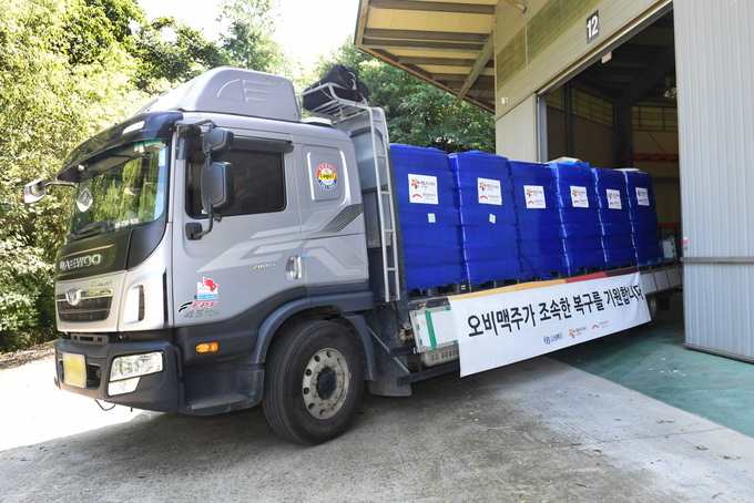 오비맥주 생수를 실은 차량이 7일 희망브리지 파주 물류센터에서 강원도 동해시청으로 출발하고 있다(사진=오비맥주)