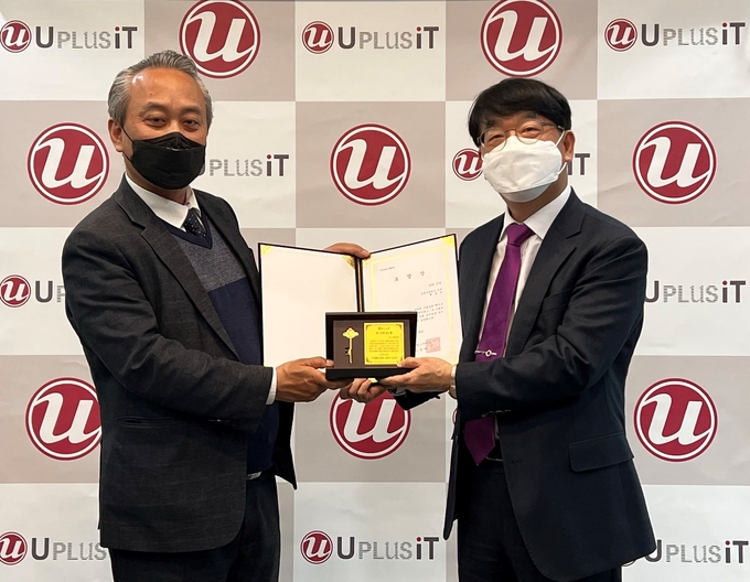 김상하<오른쪽>유플러스아이티 대표이사가 원용진 유플러스아이티 전무에게 창립 15주년 장기근속 표창을 수여하고 있다.(사진=유플러스아이티)