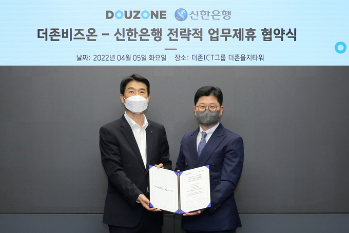 더존비즈온과 신한은행이 ‘더존DX솔루션자금대출 서비스 출시’를 위한 업무협약을 체결한 가운데, 더존비즈온 지용구 솔루션사업부문 대표(오른쪽)와 신한은행 최익성 부행장이 업무협약서를 교환하고 있다.