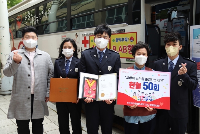 안영준<사진 중앙> 관세행정관이 생애 50번째 헌혈로 적십자헌혈유공장을 수상하고 있다.