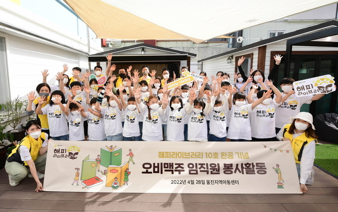 오비맥주 구자범 부사장과 임직원 봉사단, 울진지역아동센터 아동들이 행복도서관 10호 개소 축하행사에서 "10호"를 외치며 기념촬영을 하고 있다.