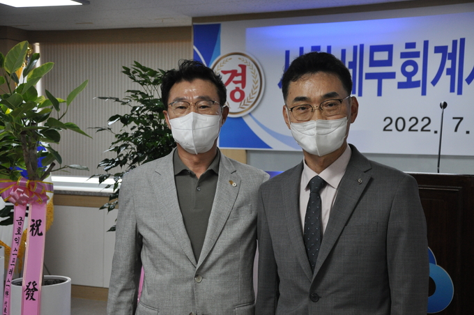 정순오 광주지방세무사회 부회장<왼쪽>이 서한도 세무사<오른쪽>에게 세무사 배지를 패용 후 기념촬영을 하고 있다.