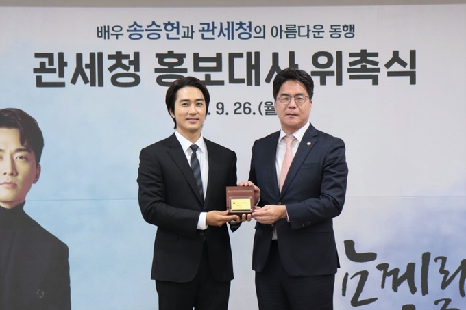 윤태식 관세청장(오른쪽)이 서울세관에서 개최된 관세청 홍보대사 위촉식에서 배우 송승헌씨에게 위촉패 수여 후 기념촬영을 하고 있다.(사진=관세청)