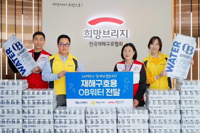 오비맥주 법무정책홍보부문 구자범 부사장(왼쪽 두번째)과 희망브리지 전국재해구호협회 김정희 사무총장(오른쪽에서 두번째)이 희망브리지 파주재해구호물류센터에서 OB워터 기증행사를 열고 기념촬영을 하고 있다. (사진=오비맥주)