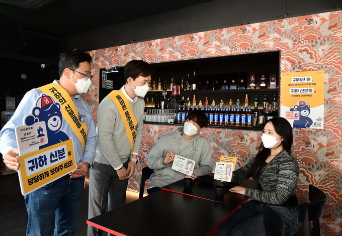 오비맥주 법무·정책홍보 부문 구자범 수석 부사장(제일 왼쪽)이 서울 옥희 강남점에서 주류 주문 시 신분증 확인을 독려하는 '귀하신분' 캠페인을 벌이고 있다.