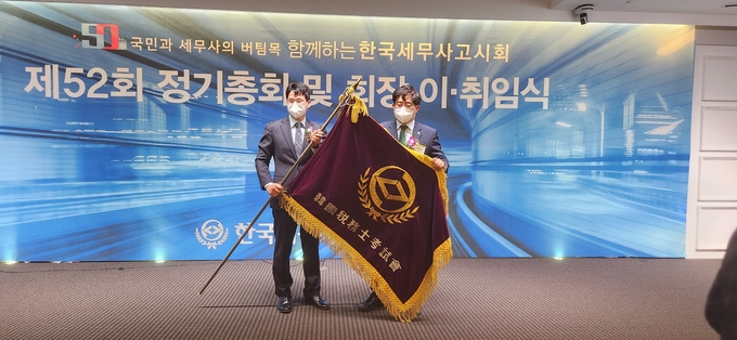 이창식(오른쪽) 회장이 이석정 신임 회장에게 회기를 전달하고 있다.