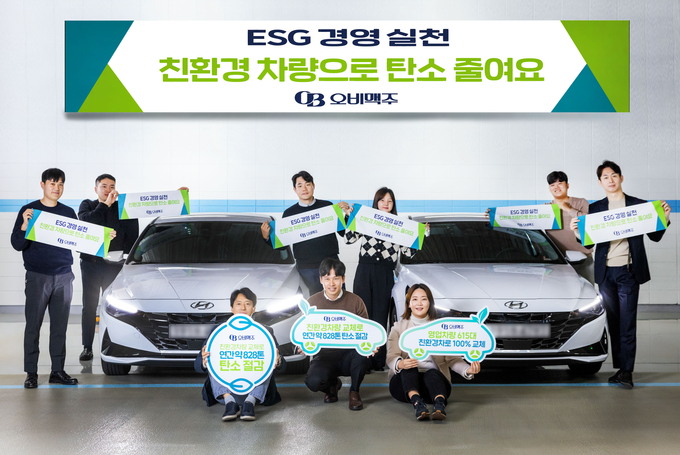 29일 오비맥주 영업부문 직원들이 영업차량을 친환경 하이브리드 차량으로 교체하고 기념 사진을 찍고 있다. <사진제공=오비맥주>