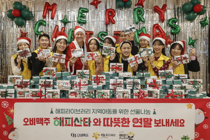 오비맥주 배하준 대표(왼쪽 네번째)와 나눔 봉사단이 전국 10개소 해피라이브러리 아동을 위한 선물꾸러미를 제작하고 기념 사진을 찍고 있다.(사진 제공 오비맥주)
