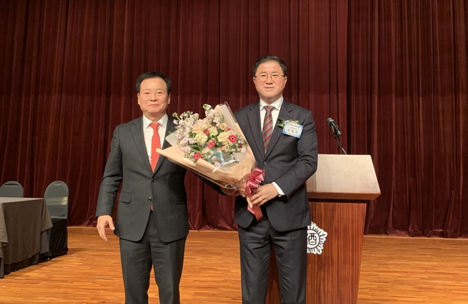 오정석 중앙회 고문이 조영조(오른쪽) 신임 중앙회장에게 꽃다발을 전달하고 있다.
