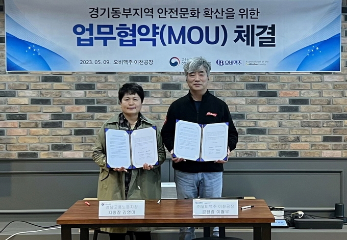 이철우 오비맥주 이천공장장(오른쪽)과 김영미 고용노동부 성남지청장(왼쪽)이 ‘경기동부지역의 안전문화 확산’을 위한 업무협약을 체결 후 기념촬영을 하고 있다. (사진=오비맥주)