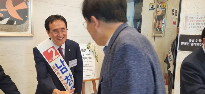 기호2번 남창현 윤리위원장 후보가 한 세무사에게 악수를 청하며 한표를 호소하고 있다. 