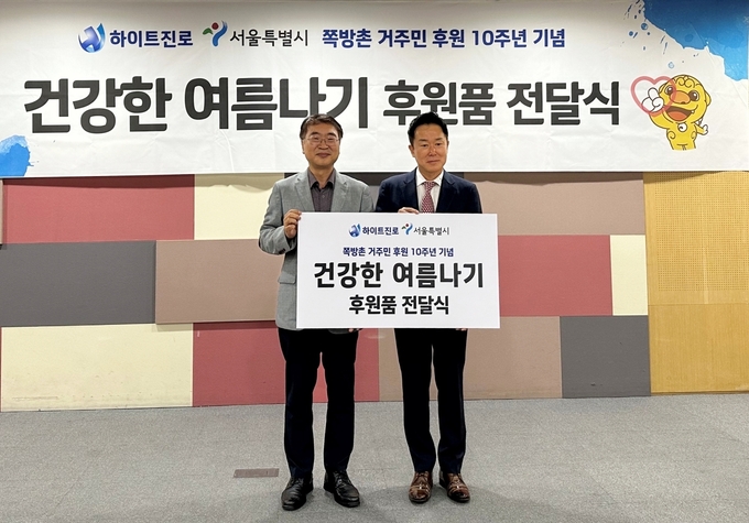 장인섭 하이트진로 전무(오른쪽) 와 김상한 서울시 복지정책실 실장이 서울시청에서 ‘건강한 여름나기’를 위한 후원품 전달식을 갖고 있다.(사진=하이트진로)