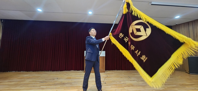 구재이 한국세무사회장이 한국세무사회기를 전달받아 흔들고 있다. 
