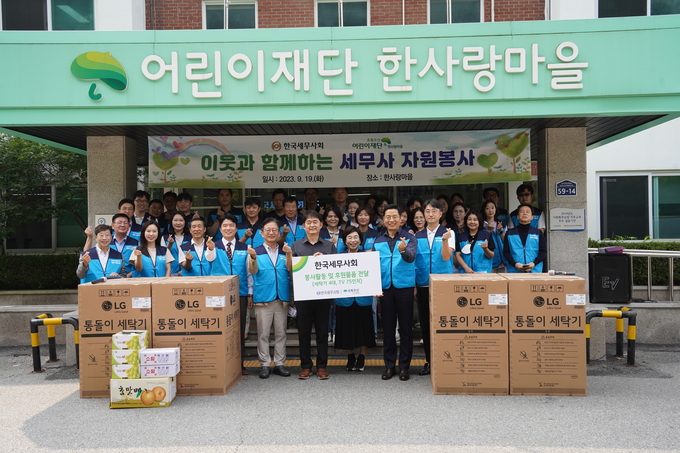 구재이 회장과 세무사회 임직원들이 한사랑마을에 세탁기 등을 기증하고 기념촬영하고 있다<앞줄 오른쪽 두번째 구재이 회장, 세번째 김귀순 사회공헌위원장>. 