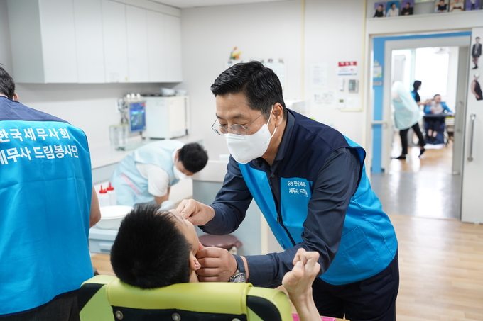 구재이 회장이 장애인의 양치를 돕고 있다. 