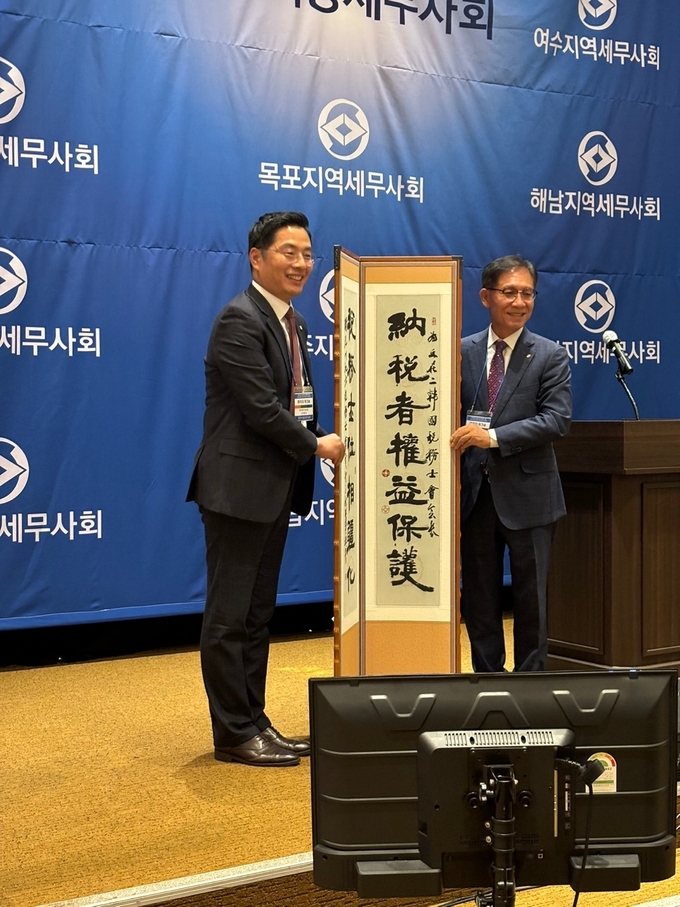 김성후 광주회장<오른쪽>이 구재이 한국세무사회장에게 '납세자 권익 보호' 족자를 전달하고 있다.