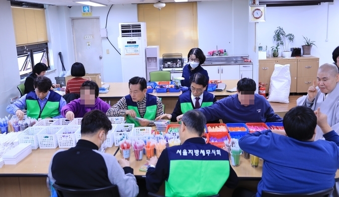 임채수 회장과 서울회 임직원이 장애인들과 함께 제품 제작·포장 작업을 하고 있다. 