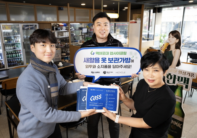 오비맥주 영업 담당자들이 맥아포대로 제작한 ‘새활용 외투 보관가방’을 족발상회 방이점 점장(맨 오른쪽)에게 전달하고 있다. (사진=오비맥주)