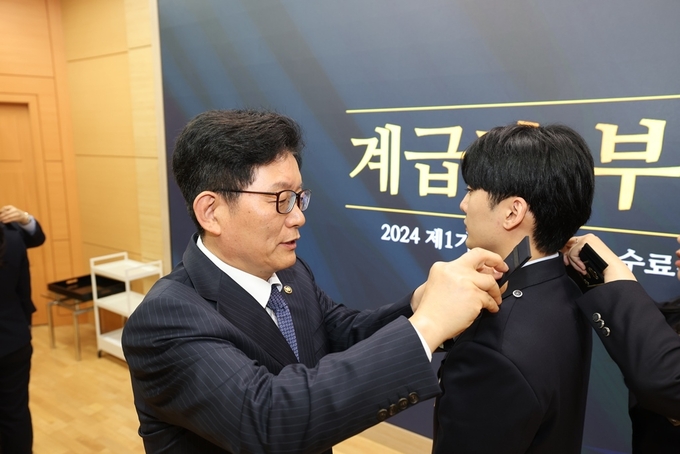 고광효 관세청장<왼쪽>이 26일 관세인재개발원에서 개최한 `2024년 제1기 관세청 입문 과정 수료식`에서 교육생에게 계급장을 부착해 주고 있다.