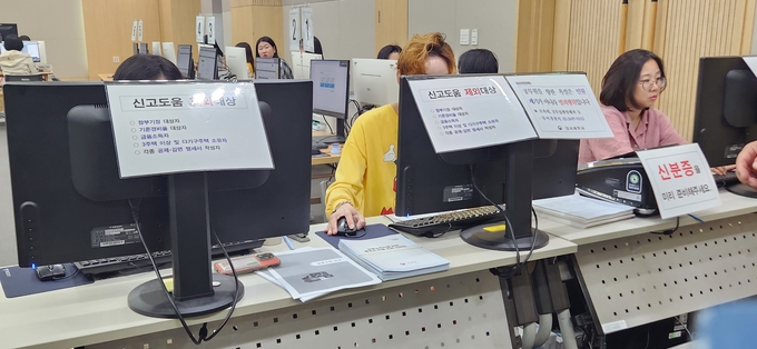 분류창구 책상 위에 금융소득자를 위한 홈택스 자료 조회가이드와 금융소득신고 안내 유인물이 놓여 있다. 