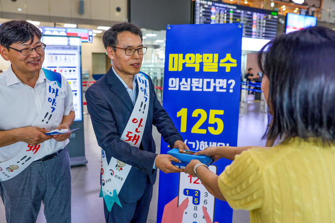 문흥호 김해공항세관장(왼쪽 2번째)이 마약 밀수 근절을 위해 해외여행시 주의사항이 기재된 리플릿과 기념품을 여행객에게 배포하고 있다.