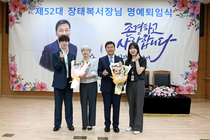 장태복 마포세무서장이 명예퇴임식에서 직원대표에게 꽃다발을 받고 기념촬영하고 있다. 
