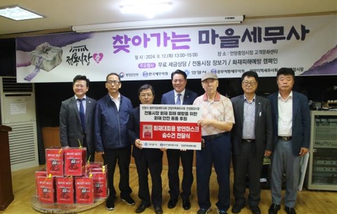 이중건 회장 등이 안양중앙시장 측에 화재대피용 방연마스크와 숨수건을 전달하고 있다. 