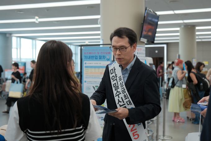문흥호 김해공항세관장이 여행객들에게 마약류 밀반입 근절 홍보물품을 나눠주고 있다.
