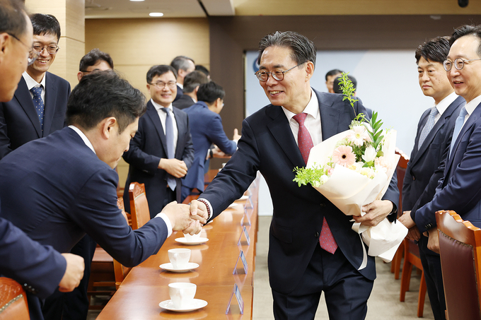 강민수 청장이 간부들로부터 꽃다발을 받고 악수를 나누고 있다.