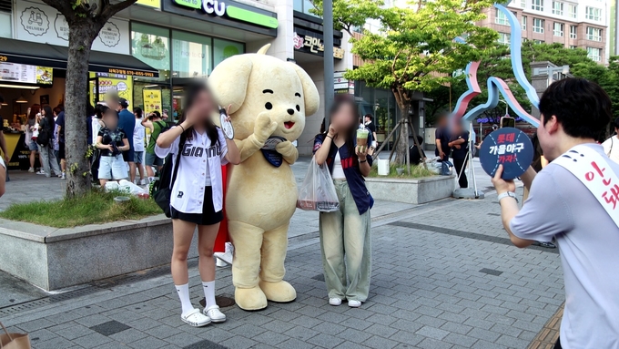 부산세관 직원들이 관세청 캐릭터 마타와 함께 사직야구장을 찾은 시민들에게 밀수 신고 홍보와 함께 기념품을 배부하고 있다.