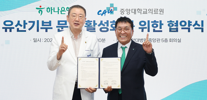 협약식에 참석한 김진우 하나은행 중앙영업그룹 부행장(사진 오른쪽)이 이철희 중앙대학교의료원장(왼쪽)과 협약서를 들고 기념촬영을 하고 있다. 