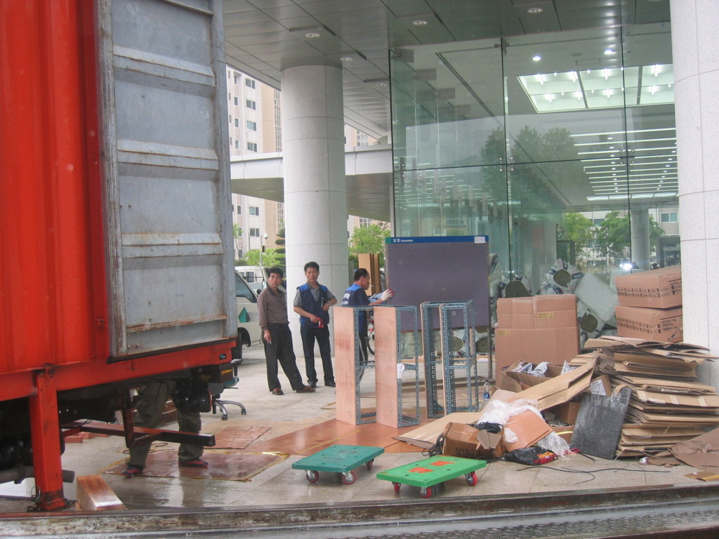 舊청사에서 출발한 이사짐센터 차량이 빗속을 뚫고 新청사에 도착하자 앞서 자리한 인부 등이 사무용품 등을 신속히 청사내 곳곳으로 이동시키고 있다.